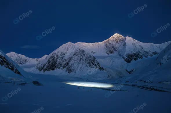 Snowy Mountain Range at Twilight with Dramatic Light Beam