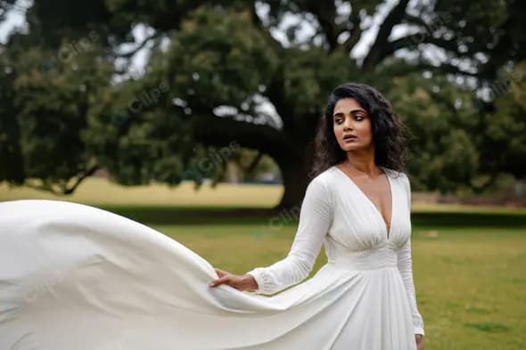 Elegant Woman in Flowing White Dress in a Scenic Garden