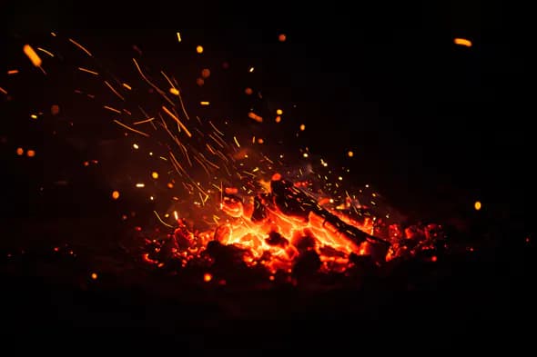 Glowing Charcoal Fire with Flying Orange Sparks Texture Background