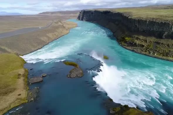 Turquoise Glacial River Cascading Through Volcanic Cliffs