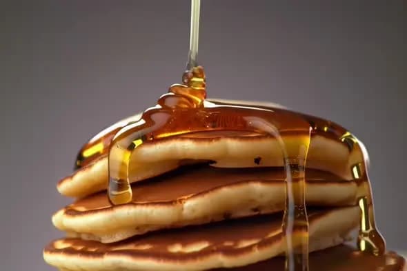 Golden Honey Drizzling onto Stack of Fresh Pancakes