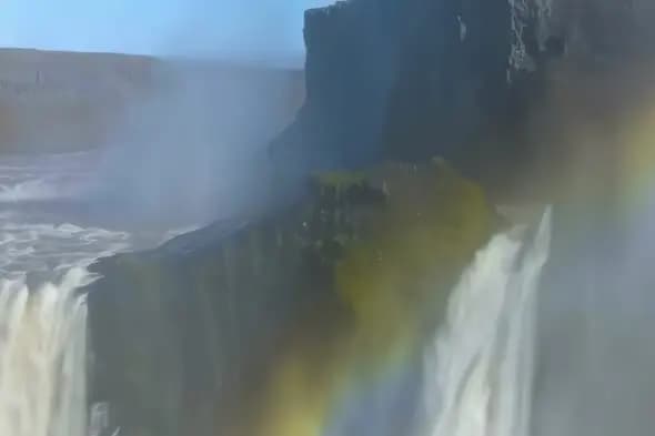 Majestic Waterfall with Rainbow Through Misty Spray
