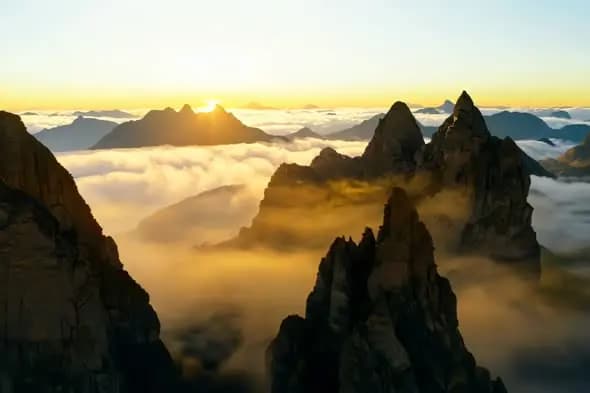 Majestic Mountain Peaks Above Golden Clouds at Sunrise