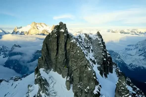 Majestic Snow-Capped Mountain Peak Above Clouds at Sunrise