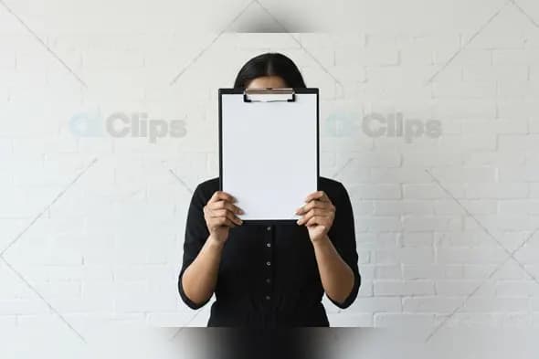 Woman Holding Blank Clipboard Against White Brick Wall