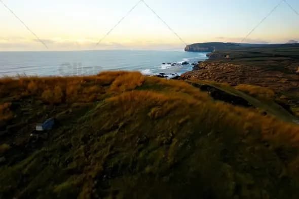 Dramatic Coastal Cliffs at Golden Hour with Wind Swept Grasslands