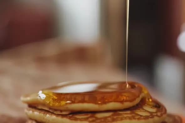 Golden Honey Drizzling onto Stack of Fresh Pancakes Close-up