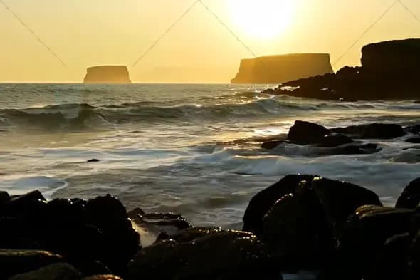 Dramatic Coastal Sunset with Crashing Waves and Rock Formations