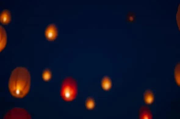 Glowing sky lanterns floating in dark night