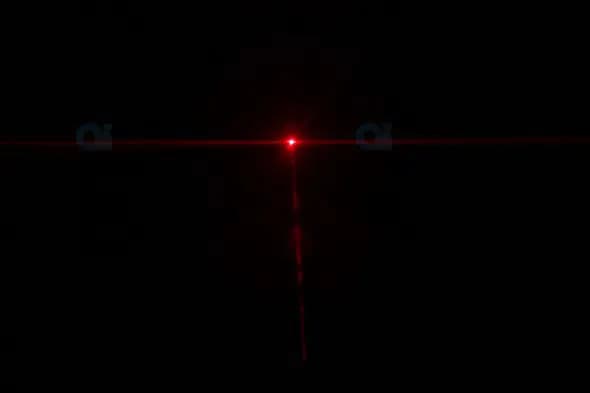 Red Laser Light Beam with Cross-Shaped Flare on Dark Background