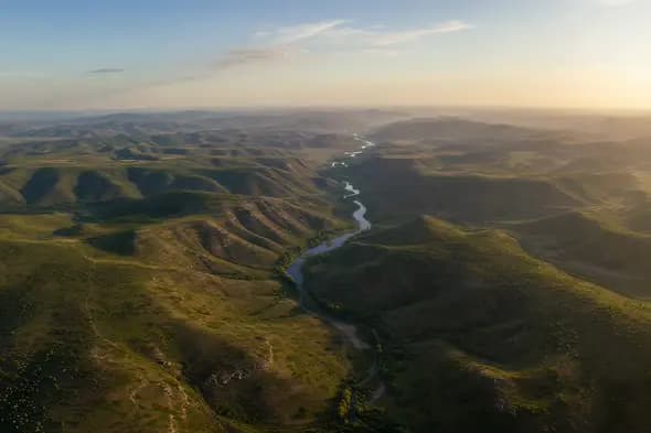 Majestic River Winding Through Vast Rolling Hills Landscape