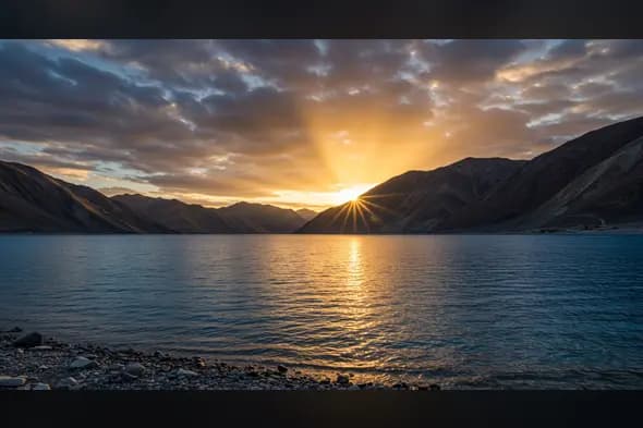 Sunset Over Mountain Lake with Golden Reflections and Dramatic Sky