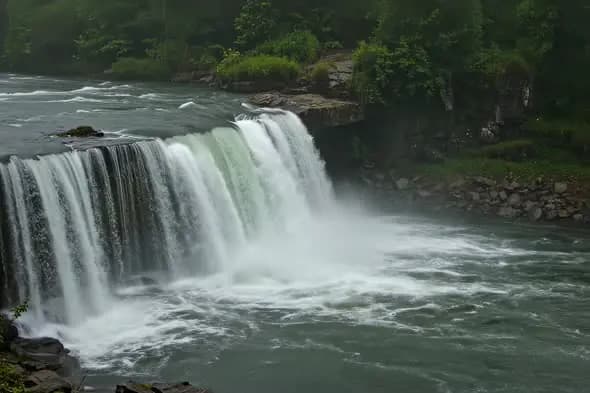 Powerful Waterfall Cascading Into Turbulent River Scenic Landscape