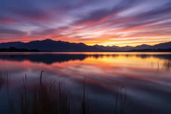 Serene Mountain Lake Reflects Vibrant Sunset Sky Colors