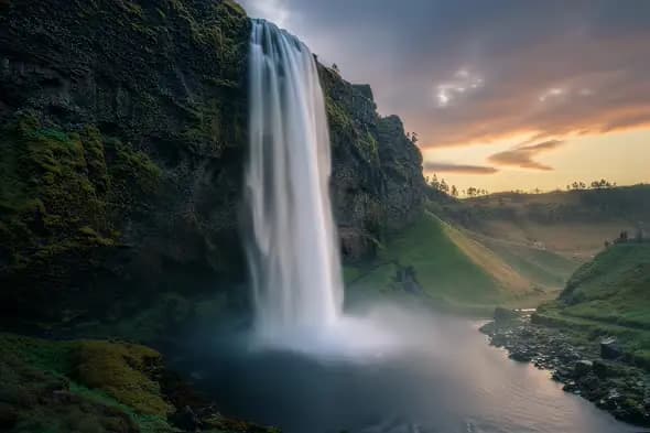 Awe-Inspiring Waterfall Plunges Amidst Sunset Hued Landscape