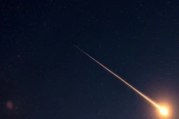 Fiery Meteor Trail Across Starry Night Sky