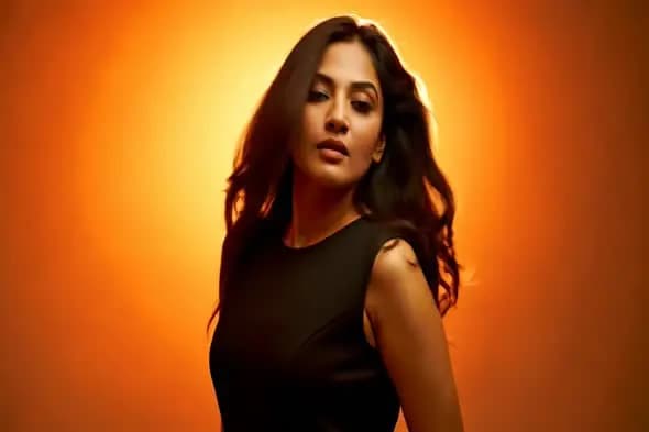 Stylish Indian Woman in Black Dress with Flowing Hair on Orange Background