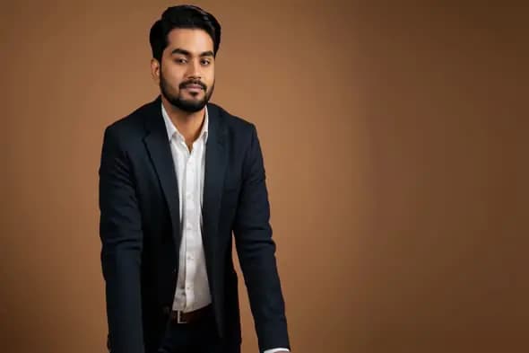 Confident Indian Businessman in Formal Attire Standing Against Brown Background