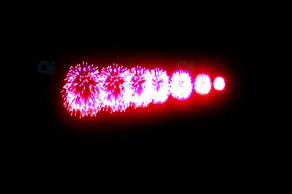 Sequenced Pink and Red Fireworks Burst Against Night Sky