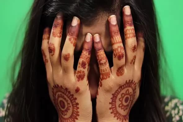 Henna-Adorned Hands Covering Face