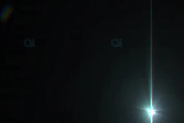 Bright Vertical Light Beam with Starburst Flare on Dark Background
