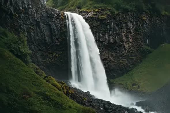 Mesmerizing Waterfall Plunges Down Mossy Volcanic Cliff Face