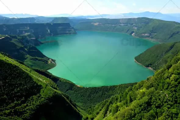 Aerial View of Turquoise Lake Surrounded by Green Mountains