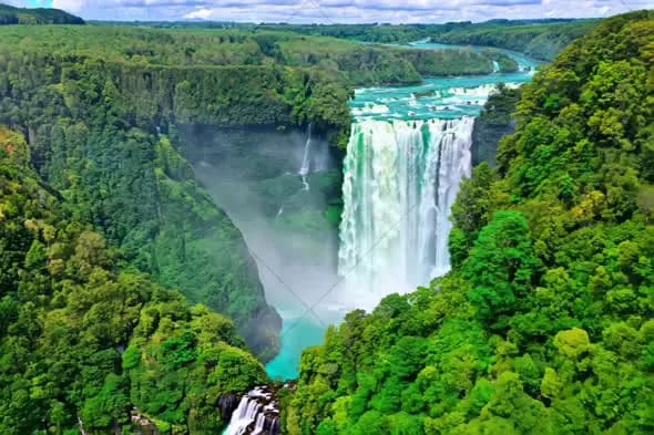 Aerial View of Majestic Waterfall Surrounded by Lush Greenery