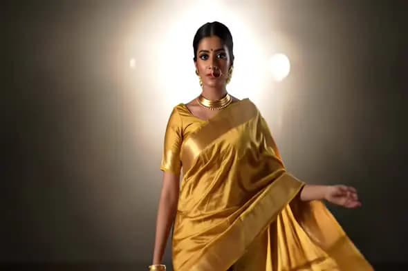 Elegant Indian Woman in Golden Saree with Traditional Jewelry on Studio Background