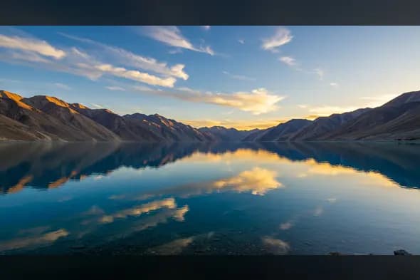 Still Reflections of Mountains and Clouds on a Pristine Blue Lake