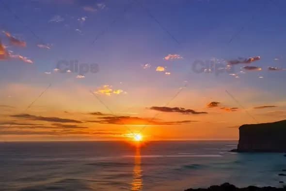 Majestic Coastal Cliff Sunset Over Calm Ocean Waters