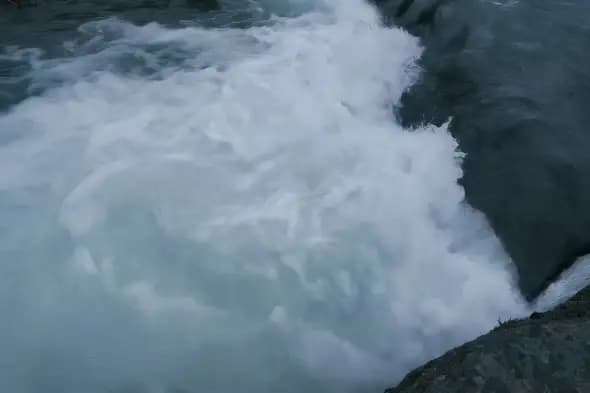 Powerful Waterfall Mist Rising Against Dark Rocky Cliff