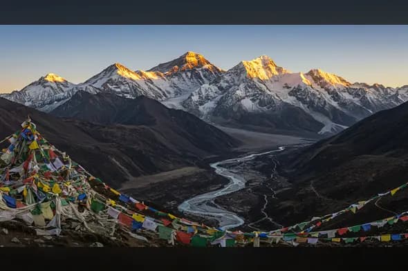 Winding Himalayan River Below Snowy Peaks at Sunrise with Prayer Flags